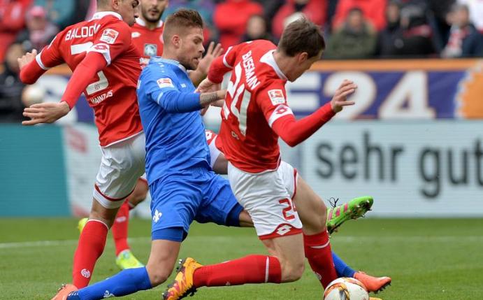 Die Mainzer Leon Balogun (l) und Gaetan Bussmann (r) nehmen Darmstadts Marcel Heller (M) in die Zange. Foto: Torsten Silz
