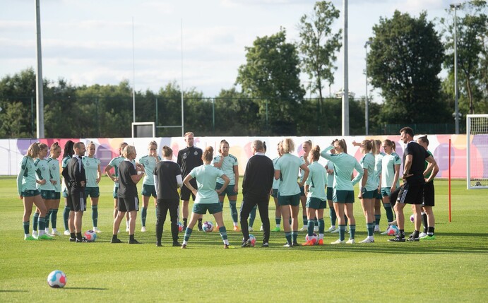 Spielerinnen und Bundestrainerin Martina Voss-Tecklenburg (l) sowie der Trainerstab stehen während einer Ansprache beieinander.
