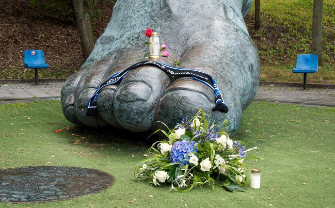 Blumen und Kerzen liegen an der überdimensionalen Bronzeskulptur vom rechten Fuß Seelers in Hamburg.