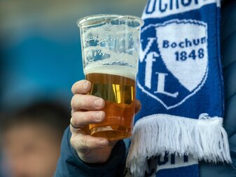 Ein Fan des VfL Bochum hält einen Becher mit Bier in der Hand. Ein Fan des VfL Bochum hält einen Becher mit Bier in der Hand.