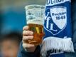 Ein Fan des VfL Bochum hält einen Becher mit Bier in der Hand.