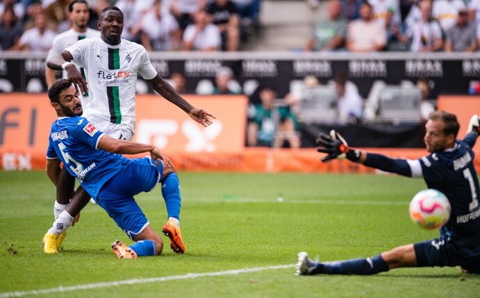 Gladbachs Marcus Thuram (M) trifft gegen Hoffenheims Ozan Kabak (l) und Torhüter Oliver Baumann zum 2:1.