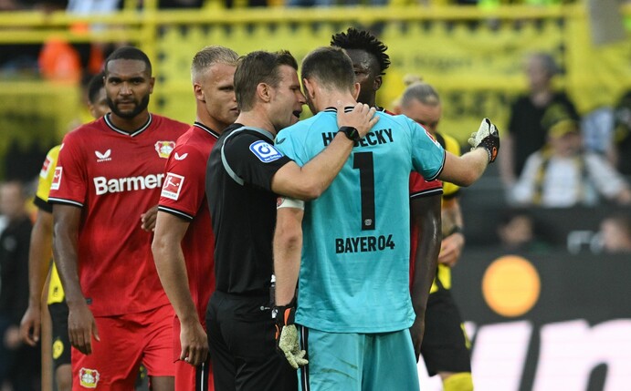Schiedsrichter Felix Brych (M) verweist Leverkusens Torwart Lukas Hradecky (r/1) des Feldes.
