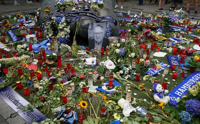 Ein Foto von Uwe Seeler und Blumen, Fan-Schals und Trauerlichter stehen an der Bronzeplastik vor dem Volksparkstadion.